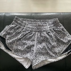Lululemon black running shorts with white and black floral pattern.